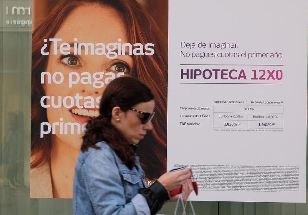 Una mujer camina junto a un escaparate con un anuncio de hipotecas, en una imagen de archivo.