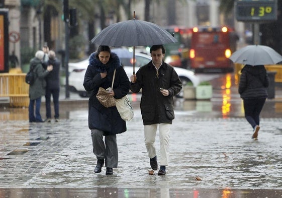 Varias personas se protegen de la lluvia en Valencia.