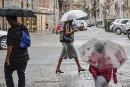 Vecinos de la ciudad de Valencia transitan por el centro bajo el temporal de lluvias.