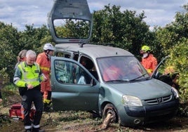 Varios bomberos y una guardia civil junto a uno de los coches siniestrados.