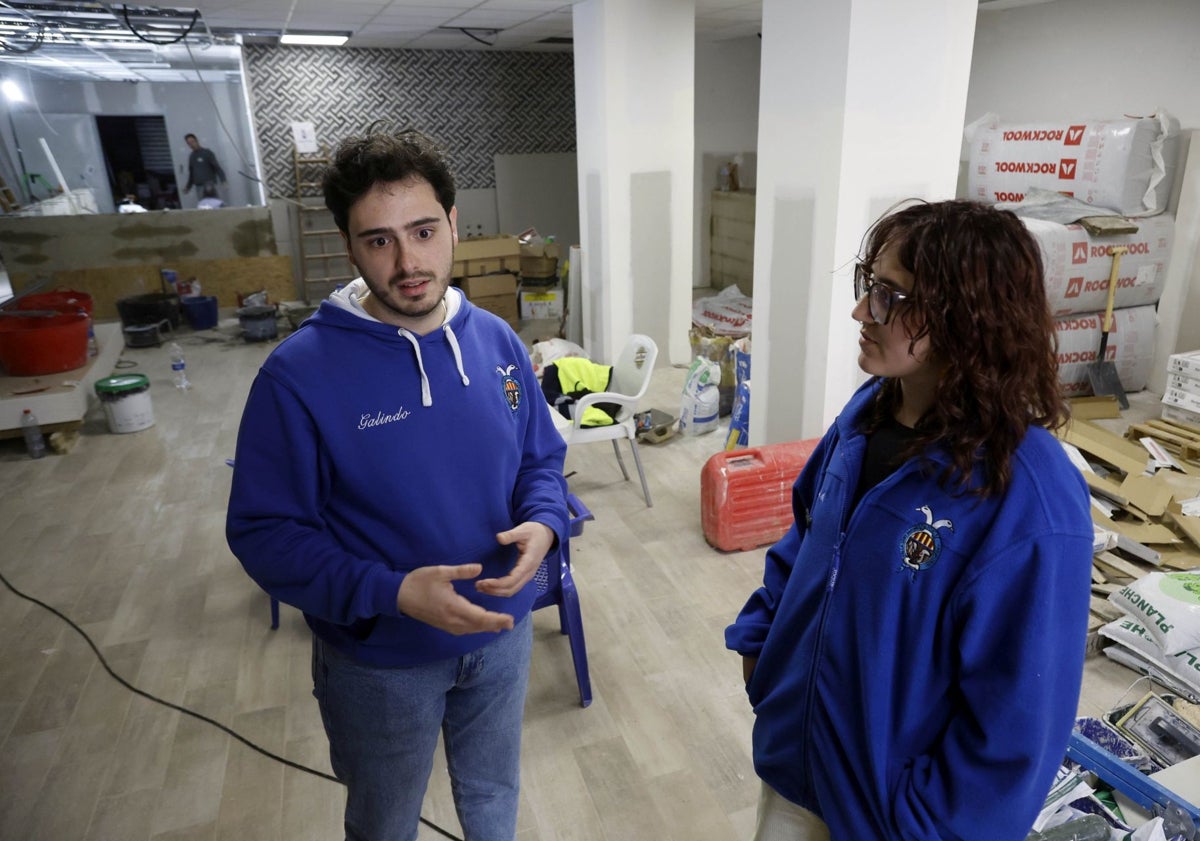 Imagen principal - Raúl Galindo, presidente de Sant Antoni de Paiporta y Judith Martínez, delegada de llibret y la marca donde se inmortaliza hasta qué altura llegó el barro.