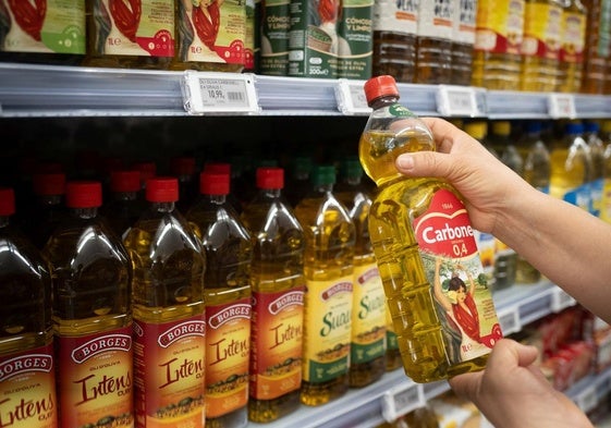Una persona sostiene una botella de aceite.