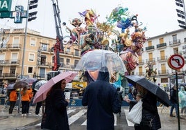 Unos paseantes se protegen de la lluvia ante una falla a medio montar.