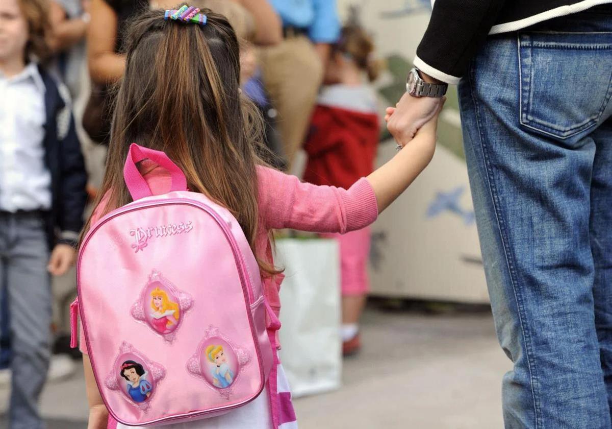 Niña coge de la mano a su madre en su primer día de colegio.