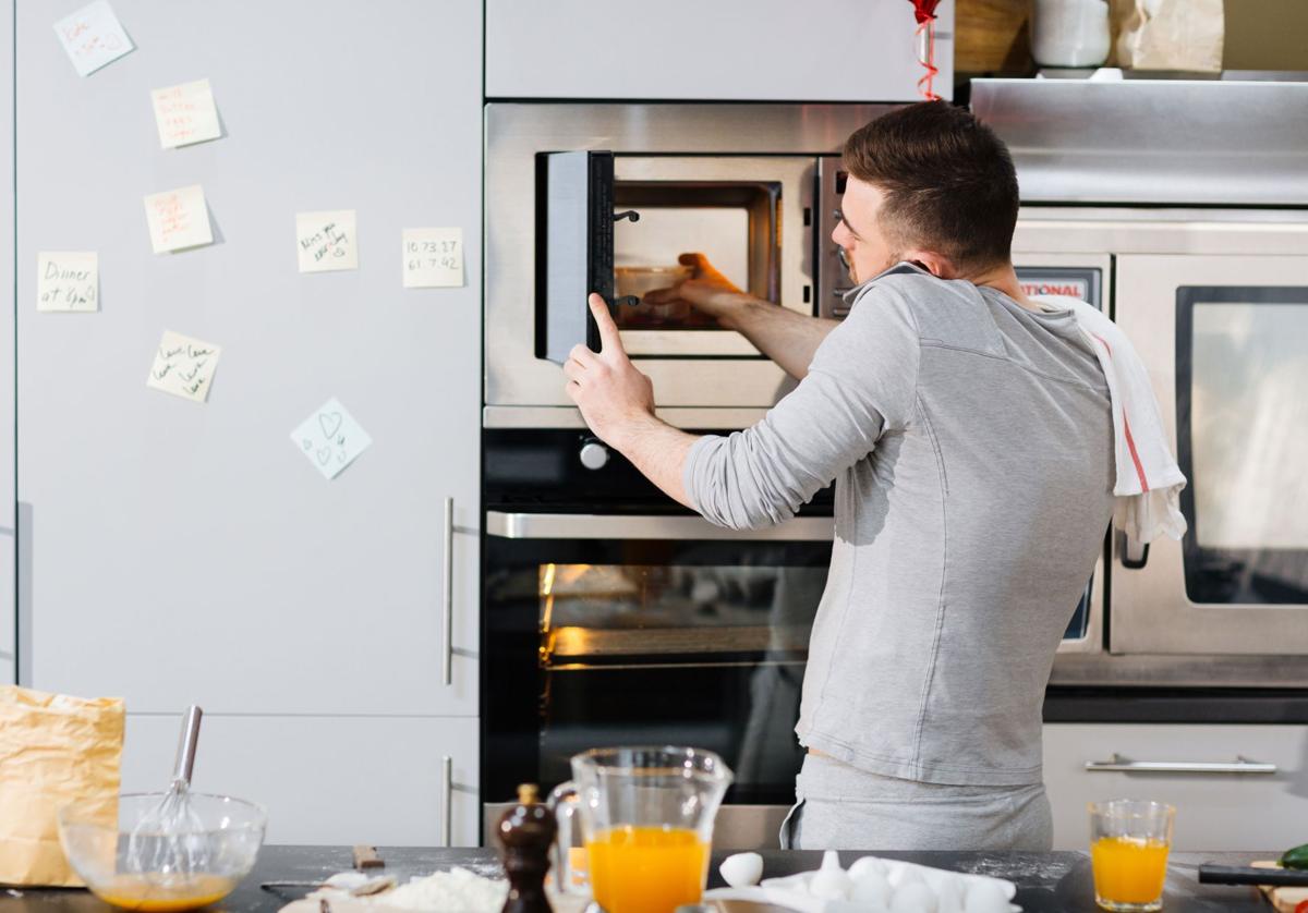 Un hombre calienta su plato en un microondas, imagen de recurso.