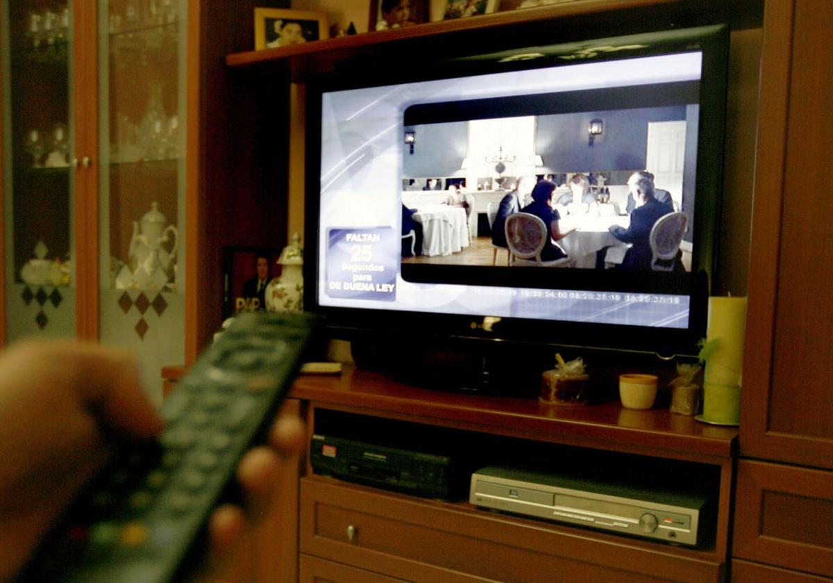 Una persona cambia de canal en su televisor.