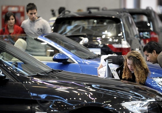Dos compradores observan el precio de un vehículo en la Feria del Automóvil.
