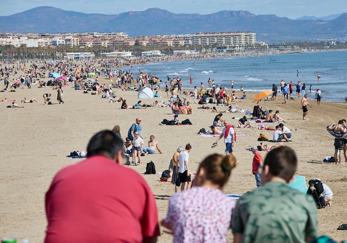 Cientos de personas llenan los arenales del Cabanyal y la Malvarrosa este viernes.