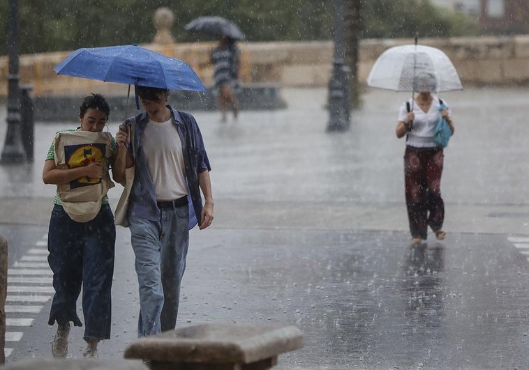 Varias personas con paraguas bajo la lluvia en Valencia.