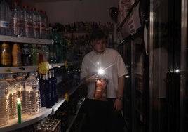 Un cliente de un supermercado recorre un pasillo con una linterna.