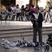 Un hombre dando de comer a las palomas en una imagen de archivo.