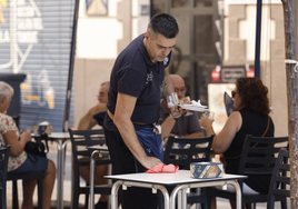 Un camarero limpia la mesa de una terraza.