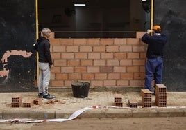 Dos operarios trabajan en la reforma de un negocio.