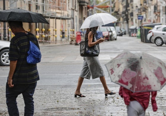 Varias personas se protegen de la lluvia en Valencia.