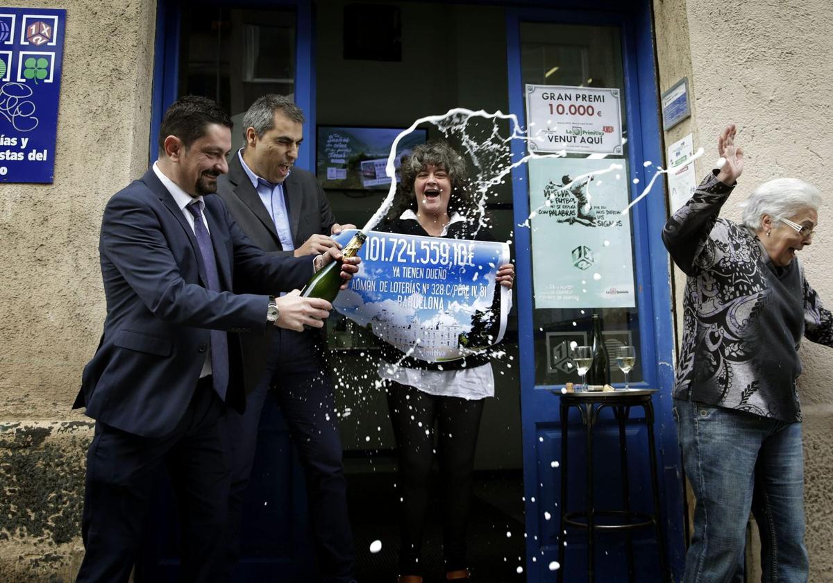 Propietarios de una administración de lotería celebran la entrega de un premio.