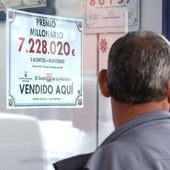 Administración de lotería junto al cartel de un premio millonario.