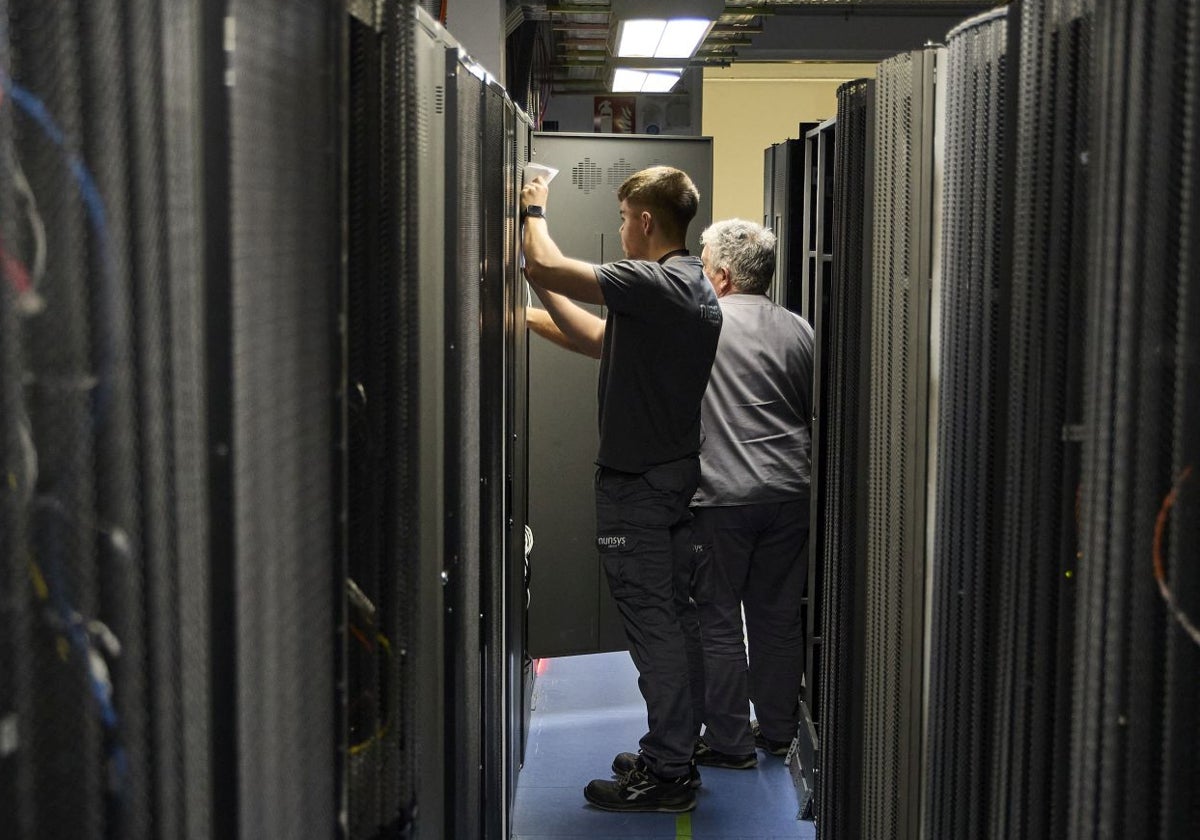 Dos operarios trabajan en el interior de un centro de datos.