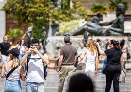 Un grupo de turistas pasea por la plaza de la Virgen de Valencia.