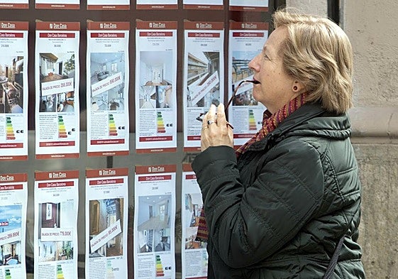 Una viandante examina los precios de una inmobiliaria.