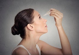 Una mujer se echa gotas en los ojos.
