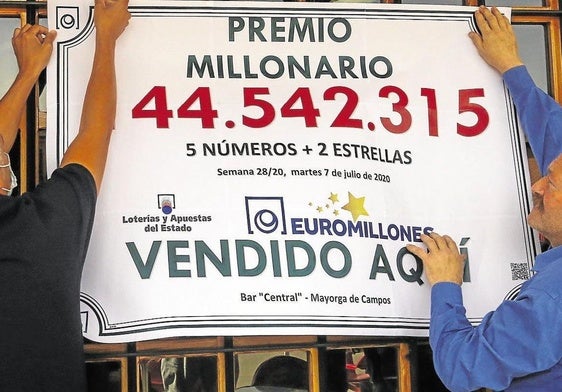 Una pareja ganadora de un premio de Euromillones cuelga un cartel.
