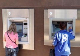 Dos mujeres retiran dinero de un cajero automático.