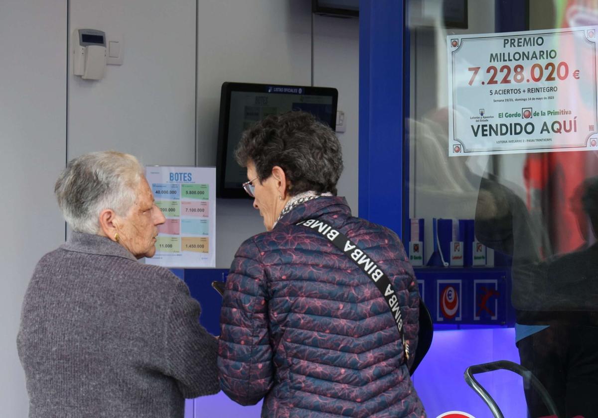 Administración de lotería junto al cartel de un premio millonario.