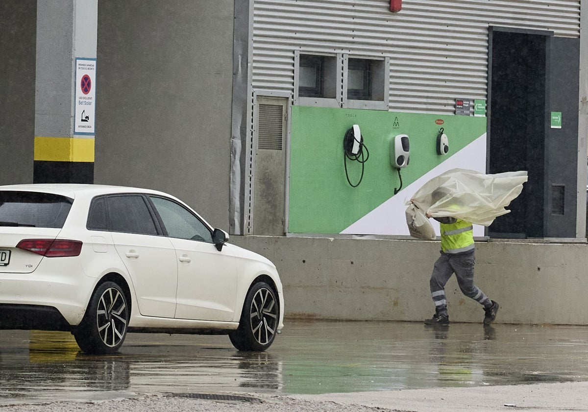 Un hombre se protege de la lluvia en un polígono industrial.