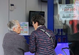Administración de lotería junto al cartel de un premio millonario.