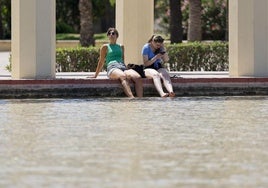 Dos personas se refrescan en una fuente de los jardines del antiguo cauce del Turia para combatir el calor