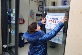 Una empleada de una administración de lotería coloca el cartel anunciador del premio. Imagen de archivo.
