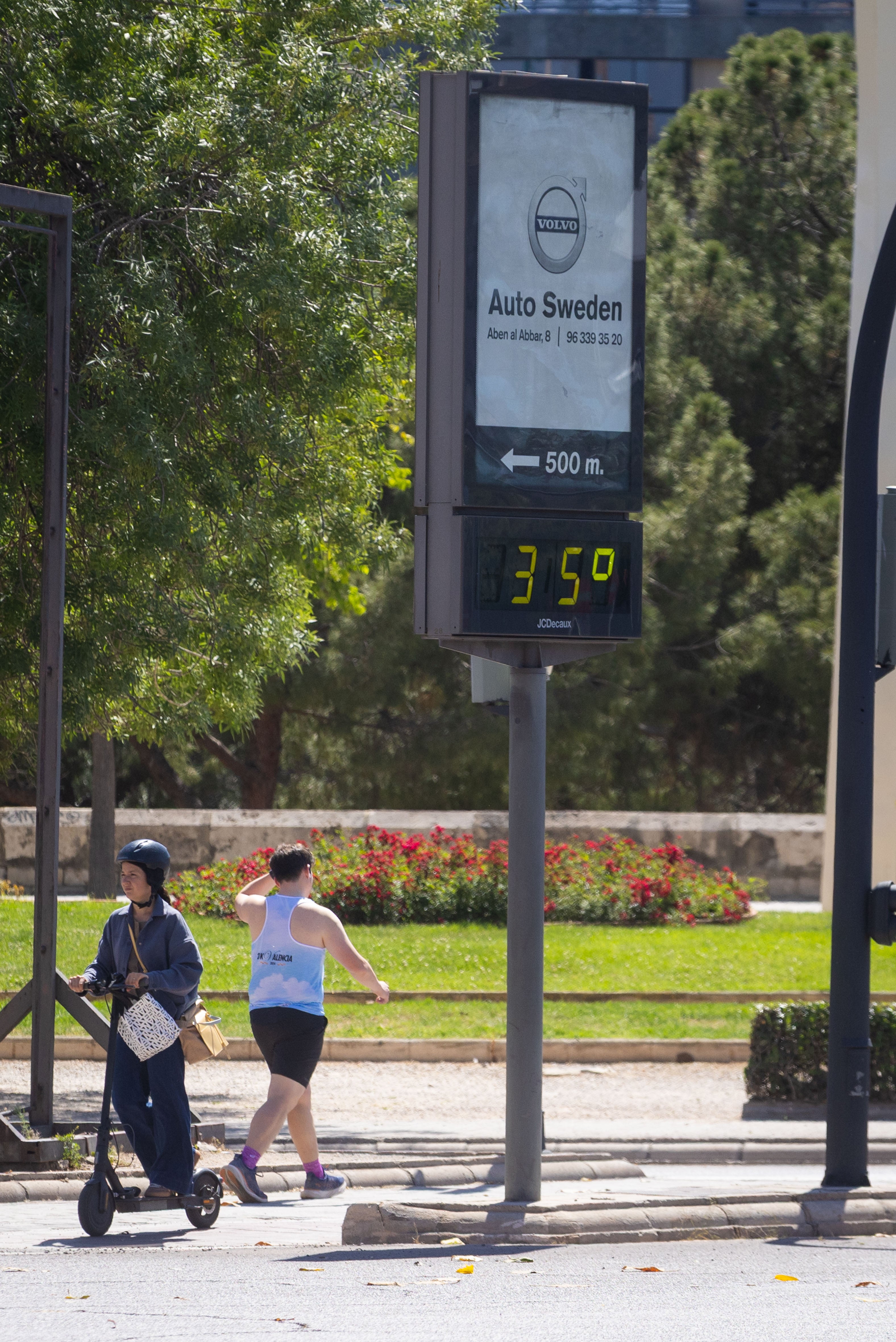 Dos personas caminan por la calle en un día de calor.