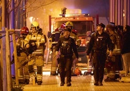 Bomberos y policías junto al edificio en llamas.