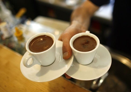Un camarero sirve dos cafés.
