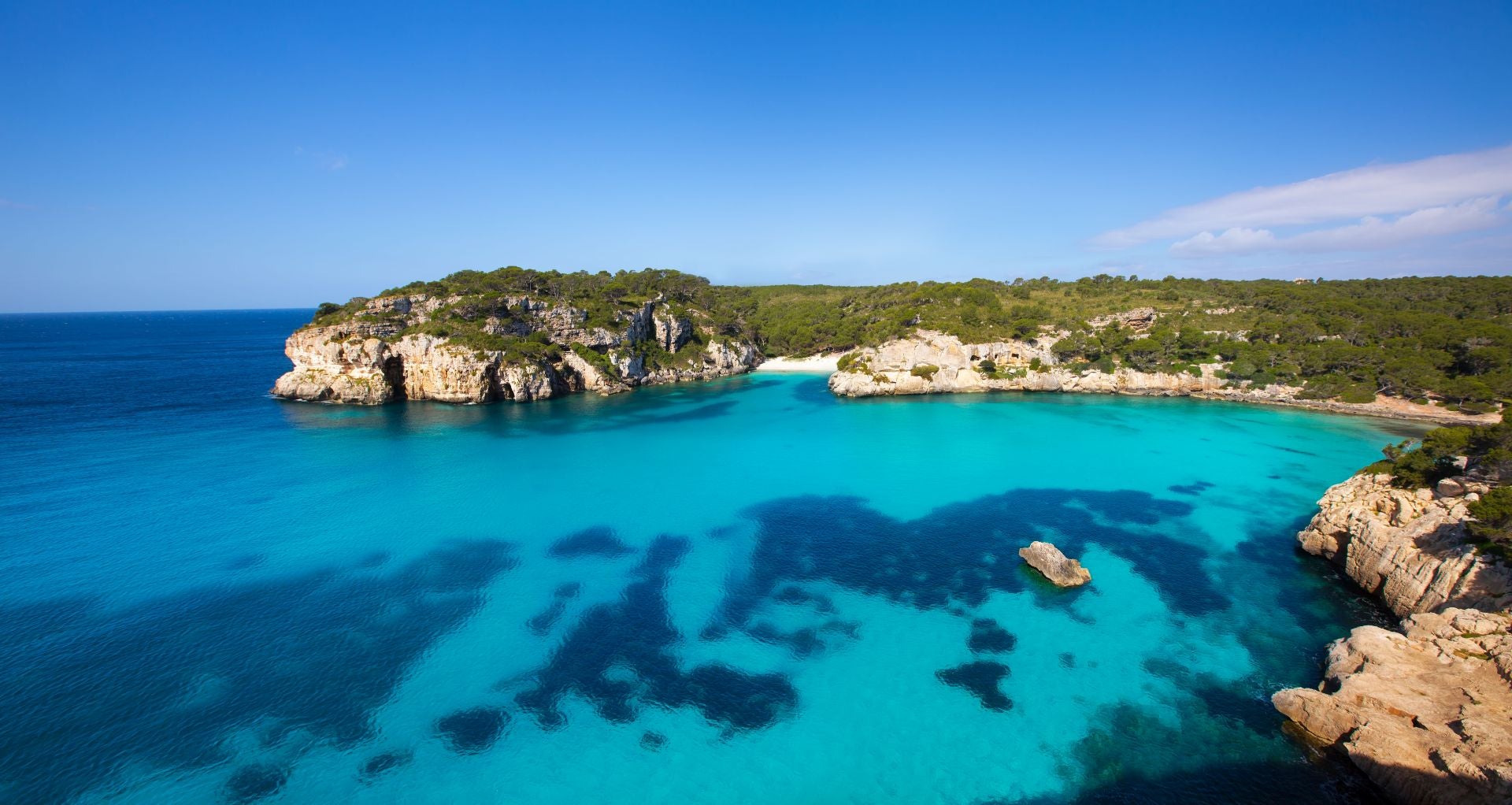 Cala Macarella, Menorca, Islas Baleares (España). Está a 14 kilómetros de Ciutadella y forma parte de Àrea Natural dEspecial Interès de la costa sur de Ciutadella. «Está considerada una de las playas más bellas de Menorca y es una de las más visitadas», indican. Protegida por el Plan Territorial Insular y por la Red Natura, «la icónica cala ofrece un paisaje espectacular: talud de arena, un agua cristalina y tranquila, una pendiente suave y una brisa marina. Este paisaje es típico del litoral meridional menorquín», destacan. «La costa gana altura, se vuelve agreste e inaccesible, excepto por la irrupción de mangas de mar, coincidentes con desembocaduras de escorrentías y barrancos, alumbrando bellas zonas de baño y excelentes refugios marítimos», añaden.