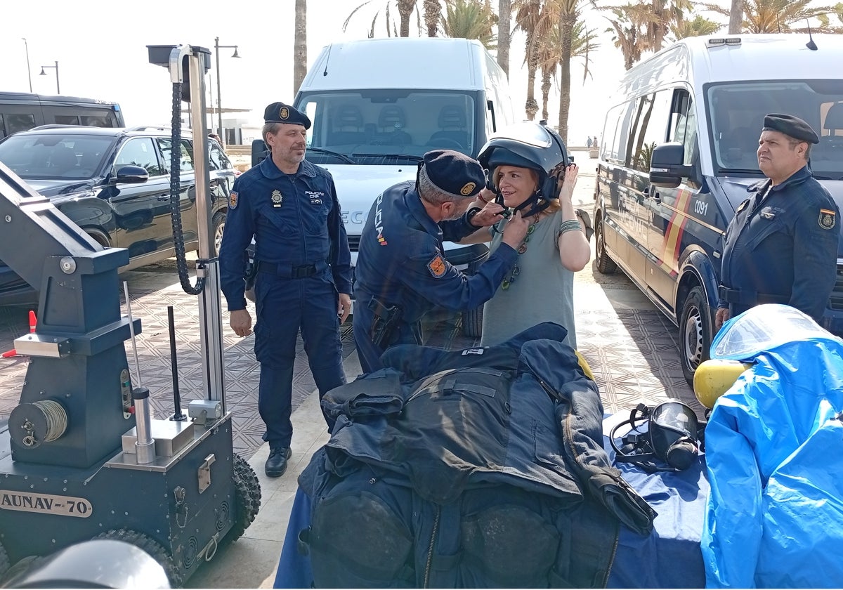 El jefe de la Unidad TEDAX-NRBQ ayuda a la delegada del Gobierno a ponerse un casco.