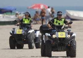Dos policías locales patrullan por un playa.