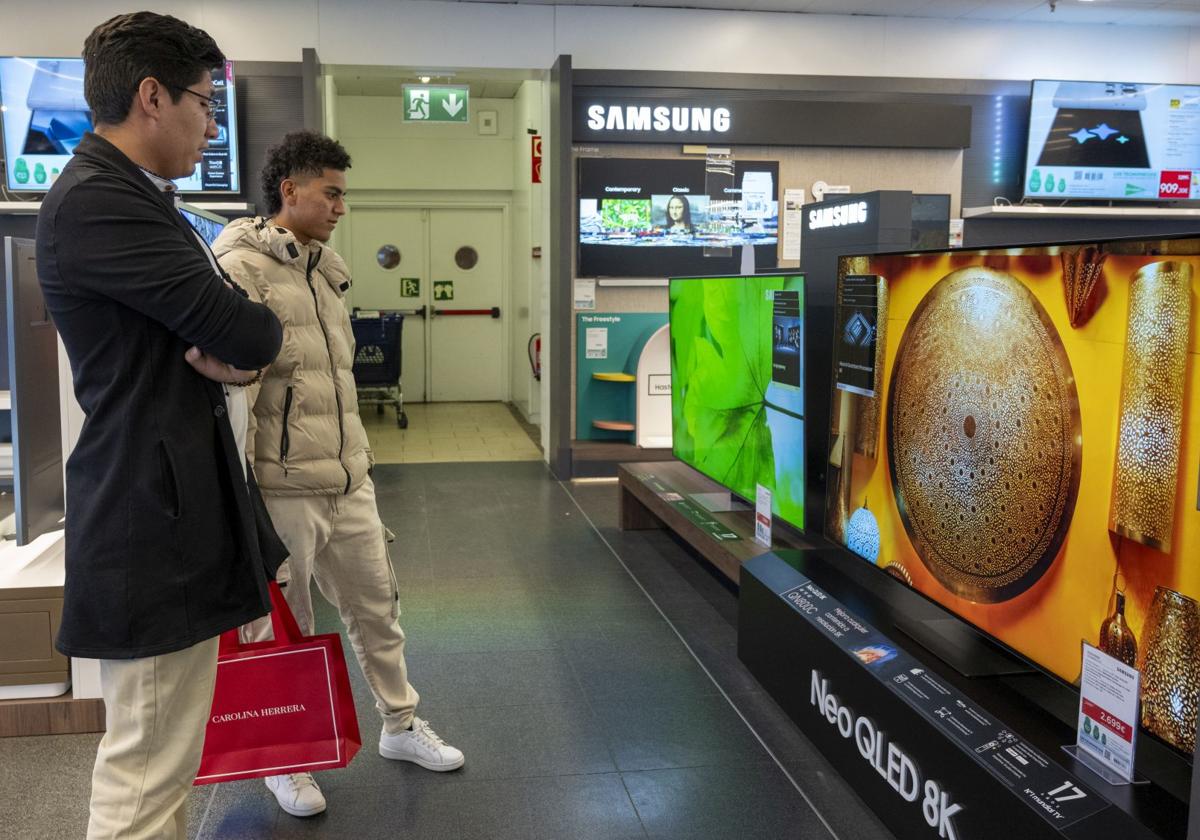 Dos clientes observan aparatos de televisión en unos grandes almacenes.