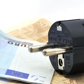 Clavija de un enchufe eléctrico y billetes de euros