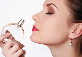 Una mujer huele un perfume.