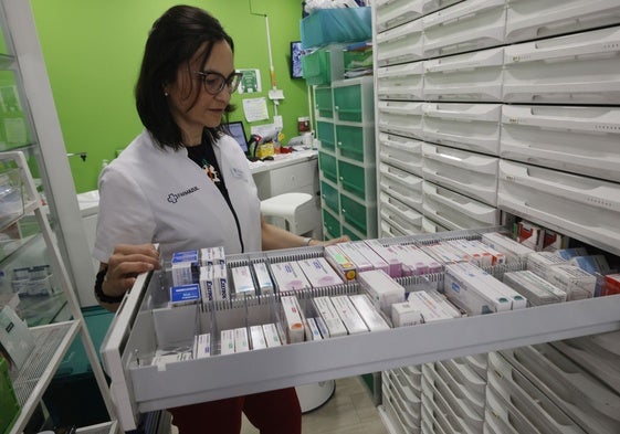 Una farmacéutica revisa los medicamentos en su establecimiento.