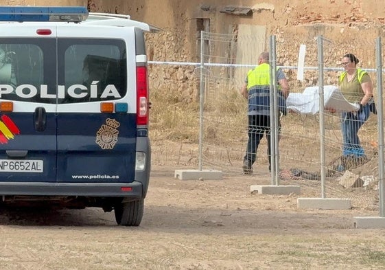 Dos empleados del retén fúnebre trasladan el cuerpo de la víctima.