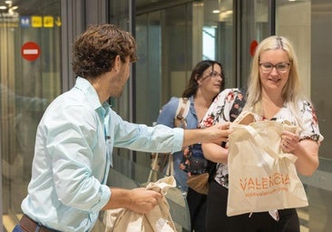 Una pasajera recibe la bolsa de cortesía de Visit Valencia.