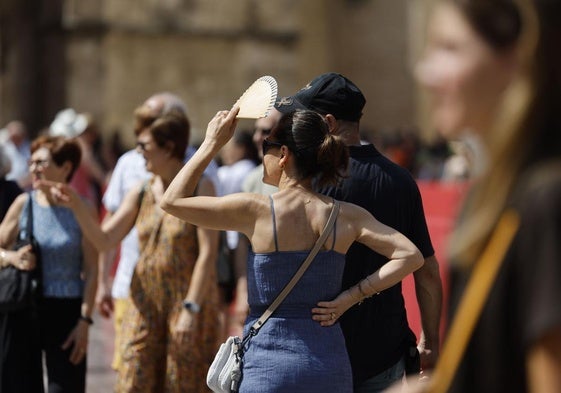 Una mujer se proteje del sol con un abanico en Valencia.