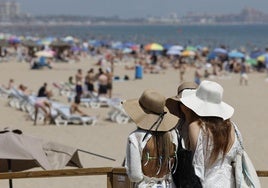Tres jóvenes observan la playa de la Malvarrosa en Valencia.