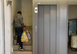Un vecino de la zona cero sube la compra por la escalera por la falta de ascensor tras la dana.