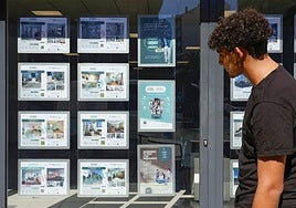 Un joven observa el escaparate de una inmobiliaria.
