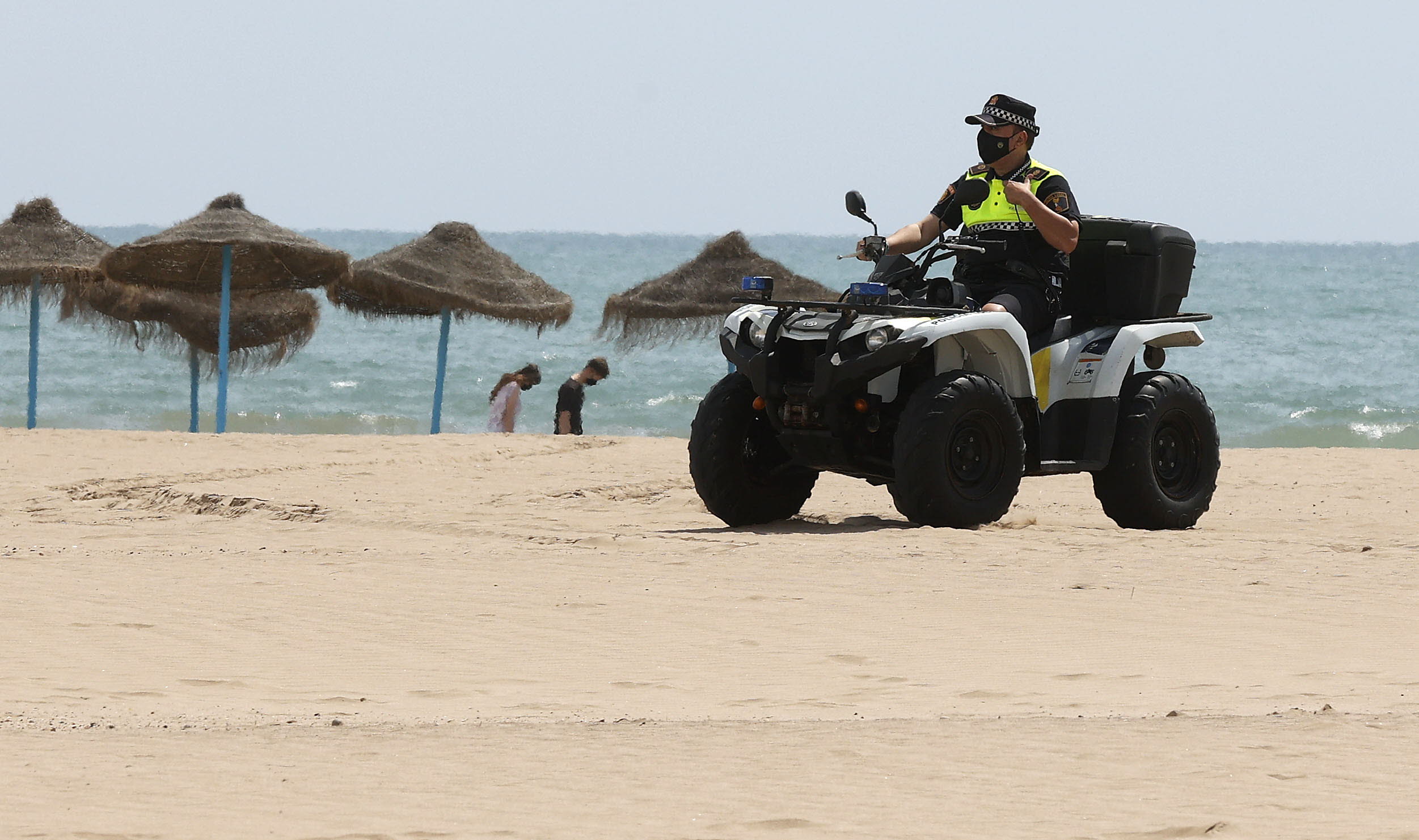Un policía local vigila en quad la playa de Valencia.