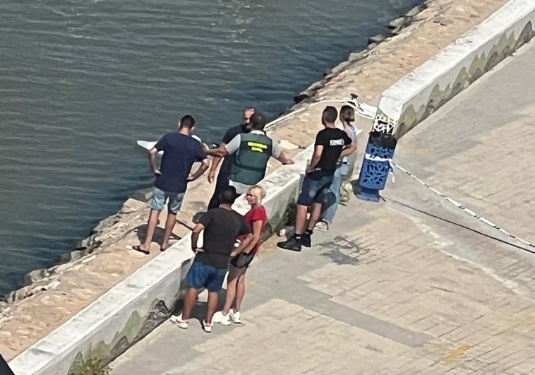 Un guardia civil y varios testigos junto al cadáver tapado con una sábana blanca.