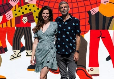 La actriz Raquel Alcalá y el director César Sabater delante del mural pintado por Cachetejack que reinterpreta el cuadro 'El abrazo' de Juan Genovés